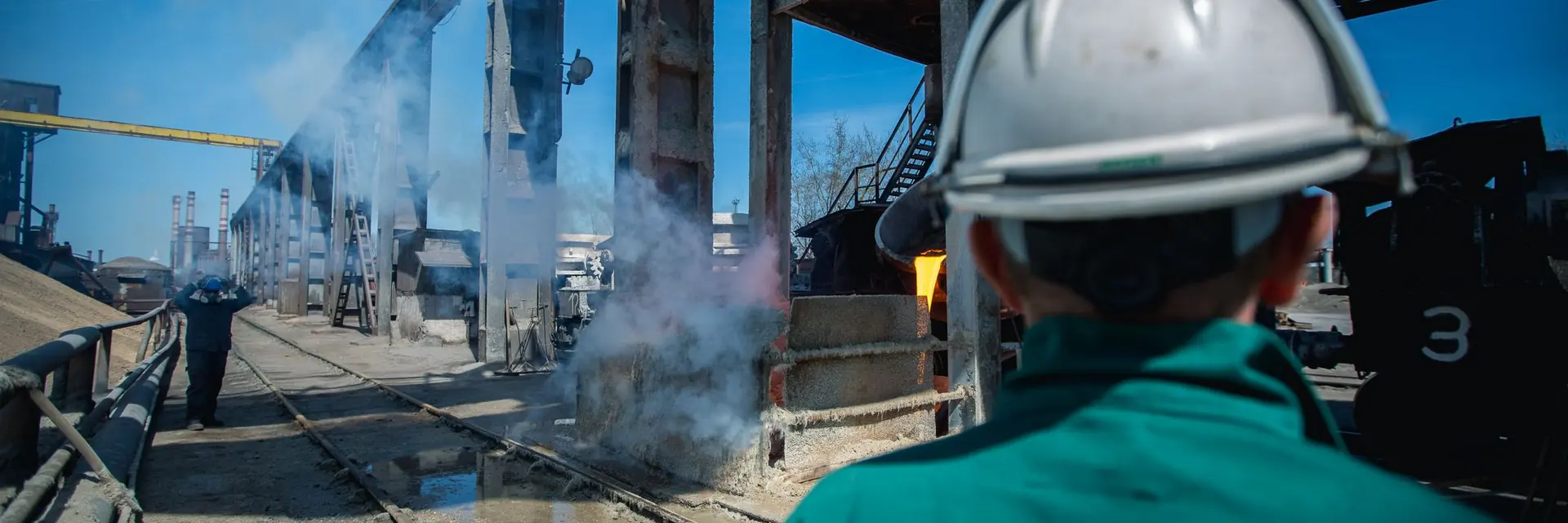 Site industriel avec un ouvrier casqué de dos